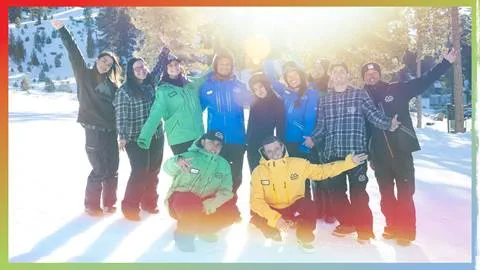A group of ten Big Bear Mountain Resort employees with hands in the air smiling at the camera