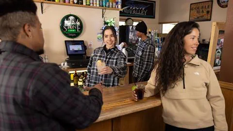 female bartender handing off a drink at big bear mountain resort's bar